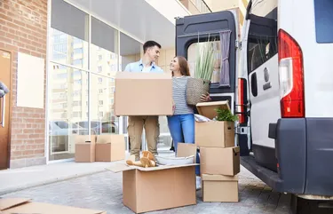 Ein Mann und eine Frau stehen vor einem Umzugswagen, bereit für den Umzug.